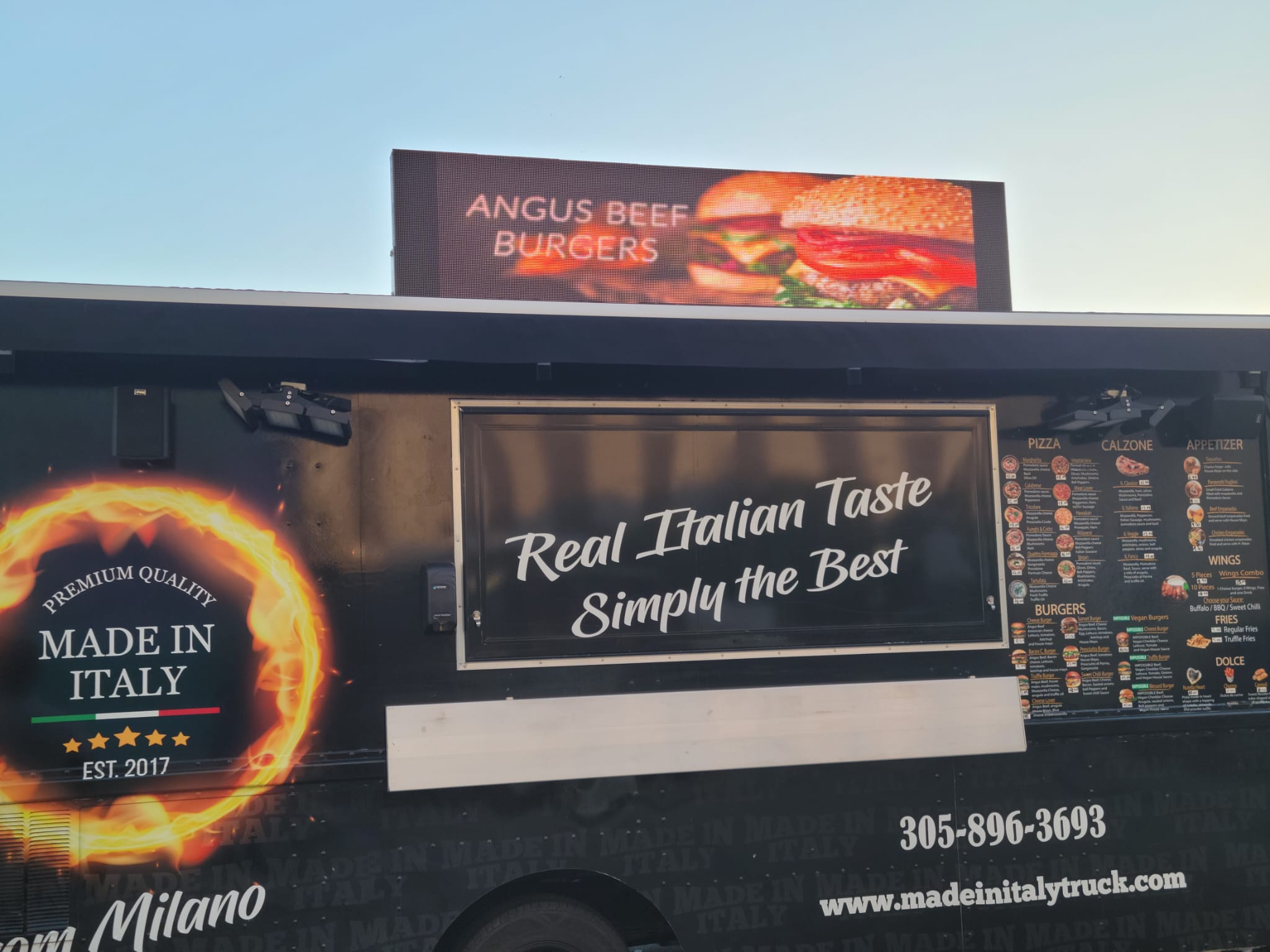 LED display mounted above a Made in Italy food truck advertising Angus beef burgers