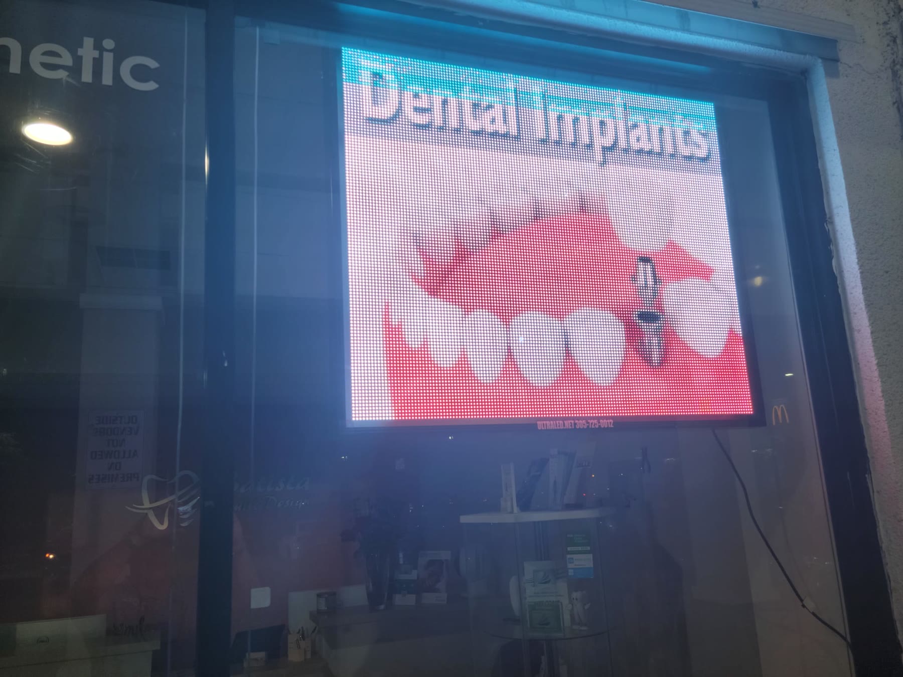 Bright window LED display advertising dental implants, seen from the street at night